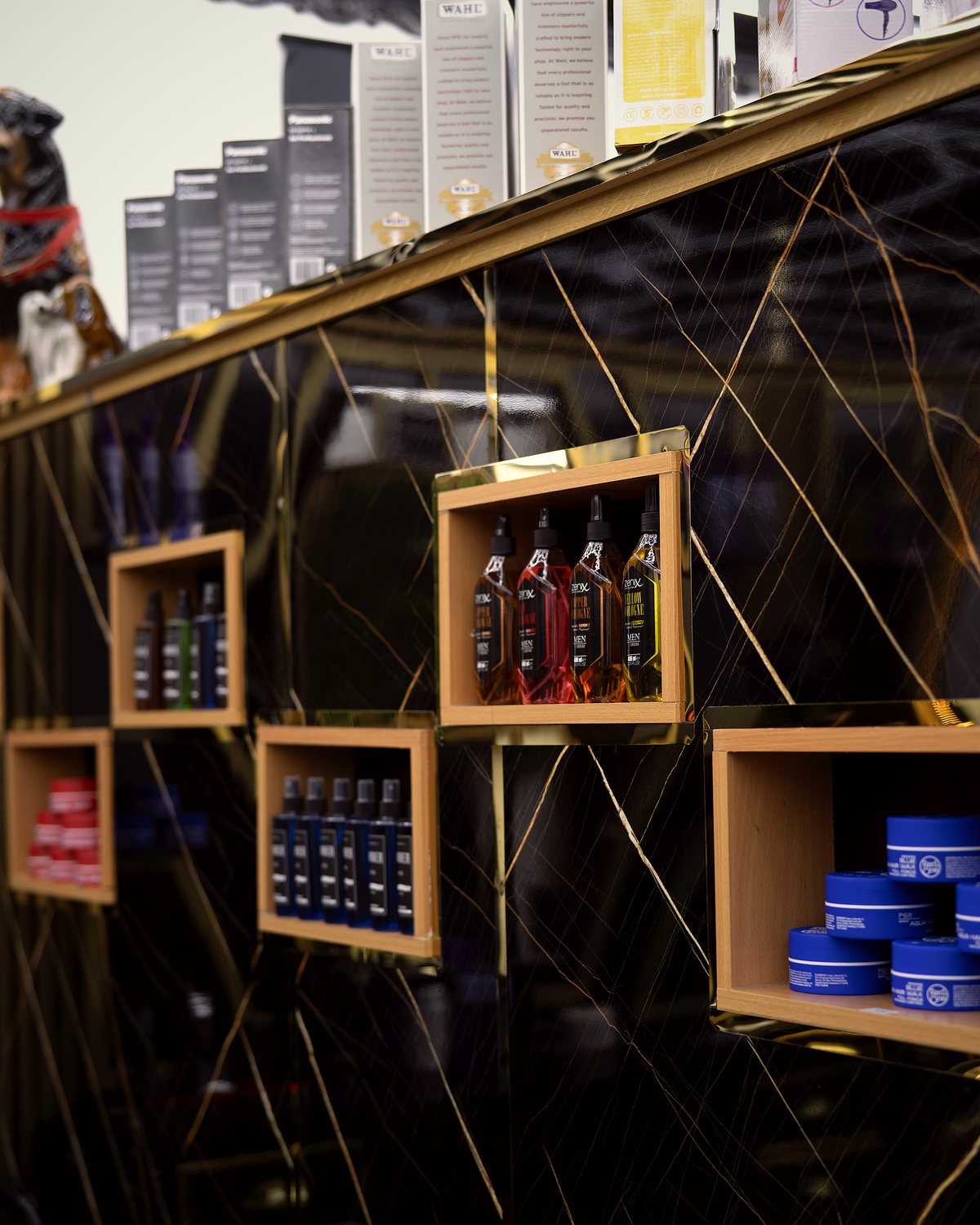 Pflege- und Styling-Produkte im gold-schwarzen Regal bei Aris Glow Cut